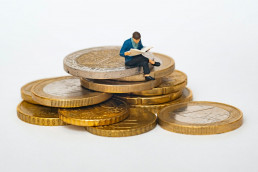 photo de mathieu stern représentant une figurine assis sur des pièces en euros