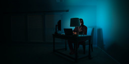 Spoofing - Un hacker est dans la pénombre derrière son ordinateur