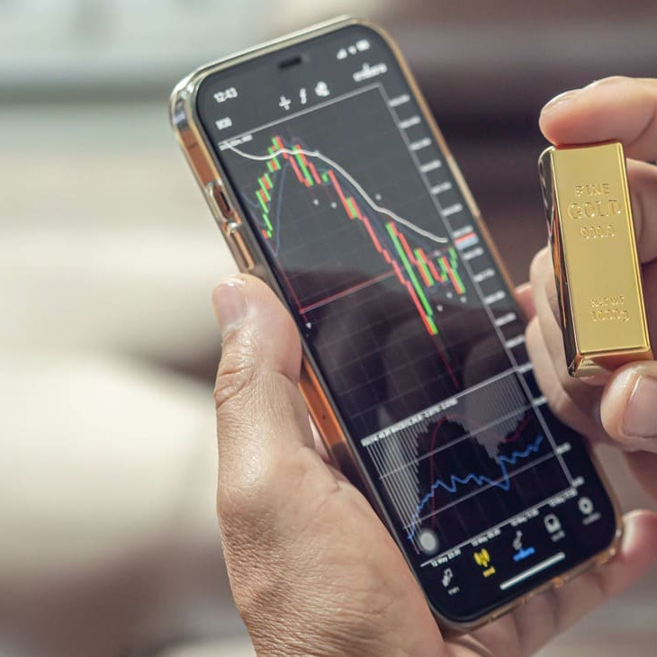 téléphone sur une application de trading montrant le cours or ainsi qu'un lingot