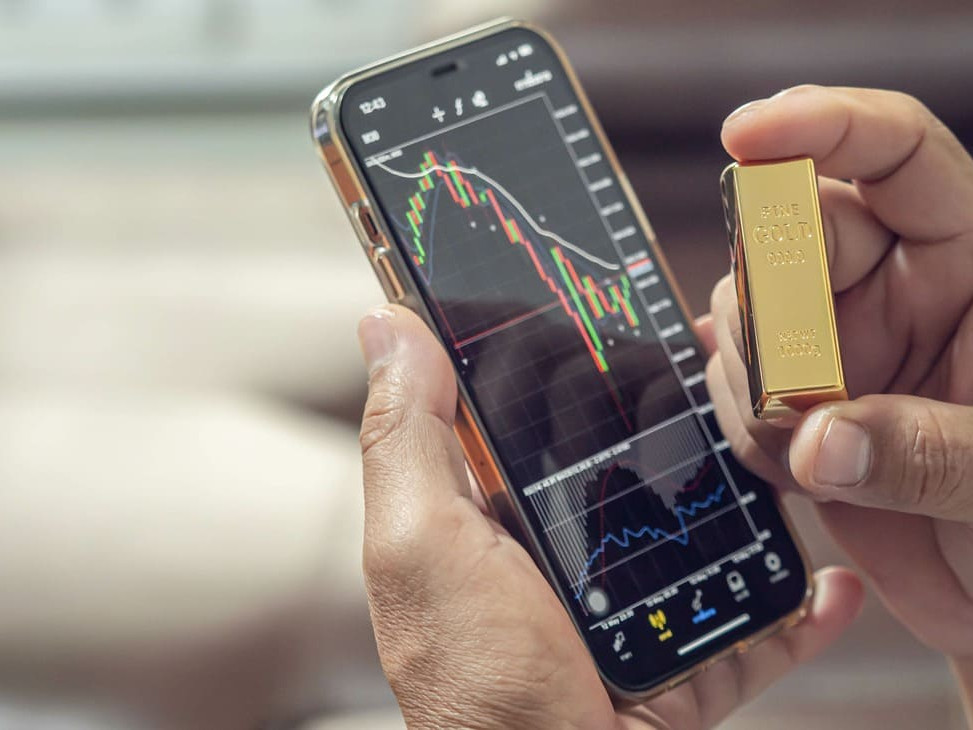 téléphone sur une application de trading montrant le cours or ainsi qu'un lingot