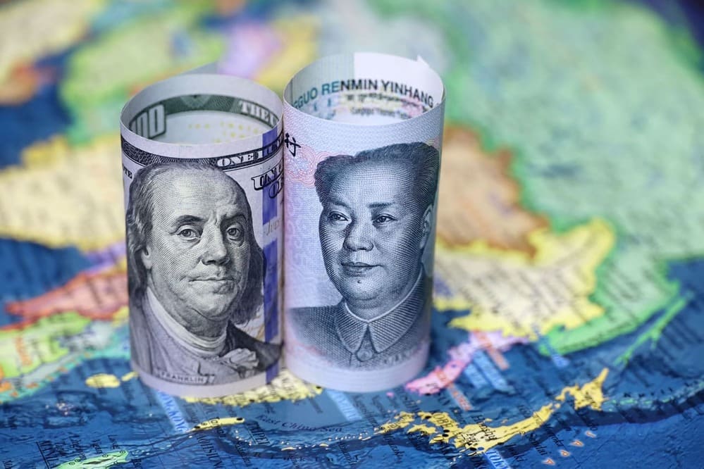 billets de dollar et yuan posés sur une carte du monde - article dédollarisation