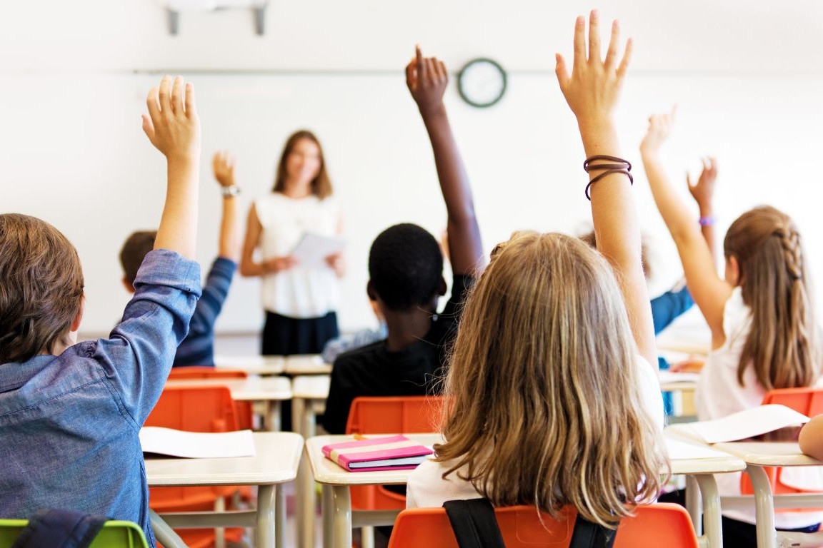 Enfants qui lèvent la main dans une classe à l'école