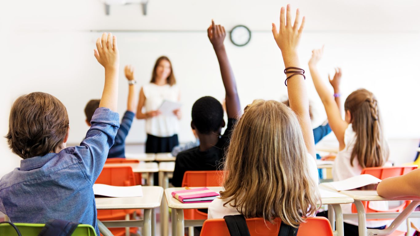 Enfants qui lèvent la main dans une classe à l'école