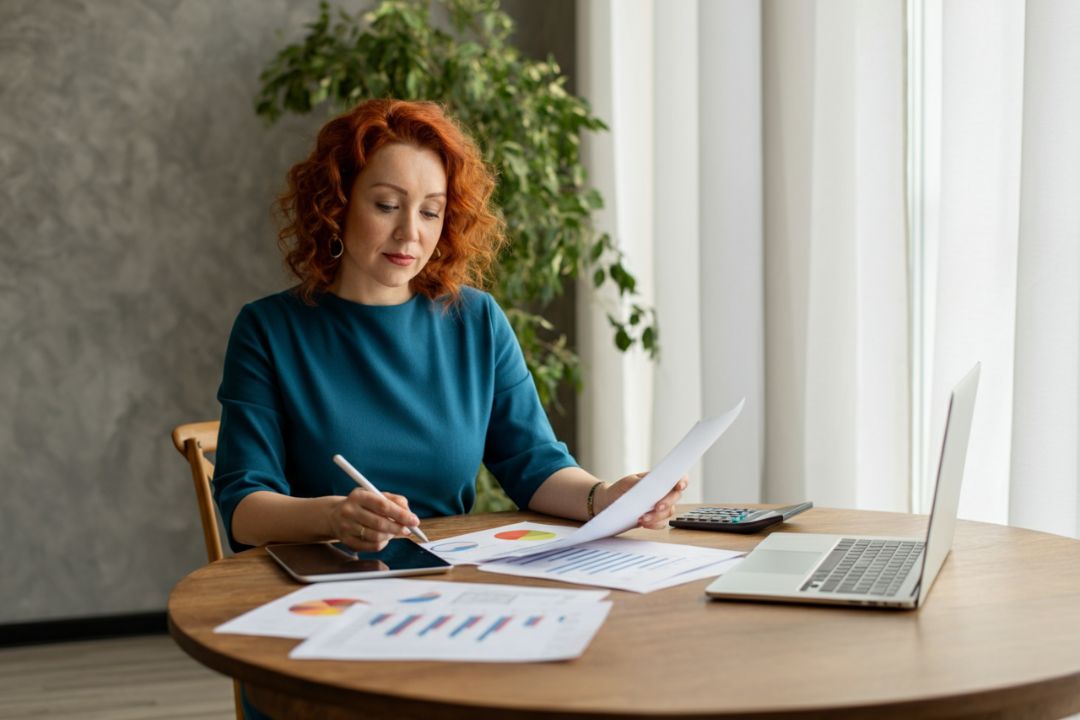 une femme d'âge moyen scrute des documents liés à l'épargne et l'investissement